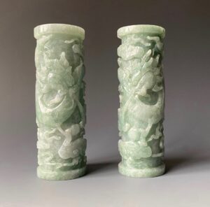 Chinese pair of jade cylinders carved with dragons. Each cylinder is made of green and white mottled jade. The dragons float in the sky surrounds by fire